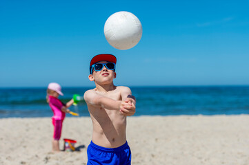 Young boy playing volleyball on beach. Summer sport concept.