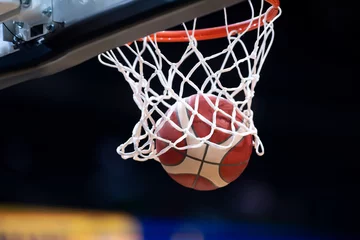 Foto op Canvas The orange basketball ball flies through the basket. Professional sport concept.. © Augustas Cetkauskas