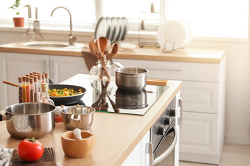 Modern electric stove and utensils in kitchen