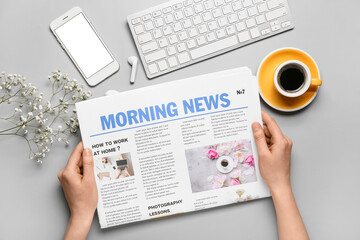 Woman reading newspaper while working in office