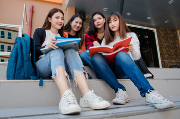 Obraz premium Group of four young attractive asian girls college students studying together in university campus outdoor looking at camera. Concept for education, friendship and college students life