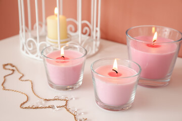 Obraz na płótnie Canvas Burning candles and accessory on shelf near color wall, closeup