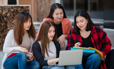 Group of four young attractive asian girls college students studying together using laptop in...
