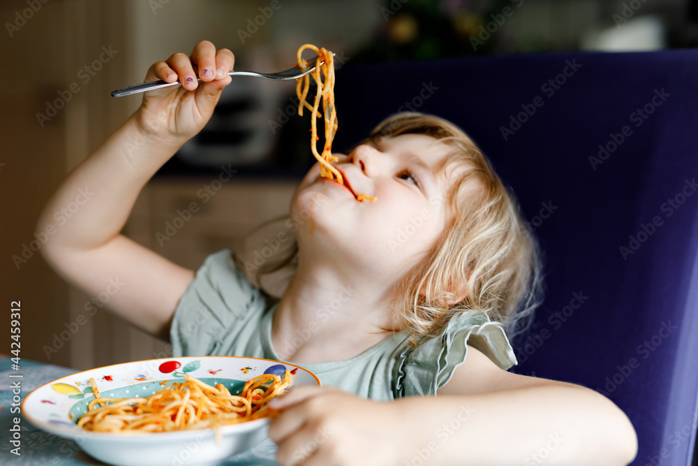 Wall mural adorable toddler girl eat pasta spaghetti with tomato bolognese with minced meat. happy preschool ch