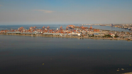 Naklejka na ściany i meble Aerial view industrial cargo port with ships and cranes, Manila. View of the cargo port and container terminal. Container cranes in Manila Bay. Cargo ship in industrial port, Philippines.