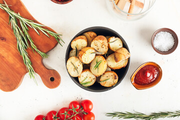 Bowl with baked potatoes on white background