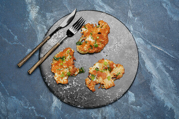 Board with tasty fried cauliflower on color background