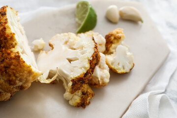 Board with tasty fried cauliflower on light background, closeup