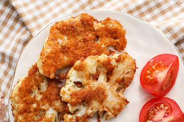 Plate with tasty fried cauliflower and tomatoes on table, closeup
