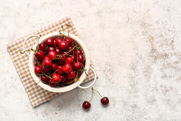 Colander with tasty ripe cherry on light background
