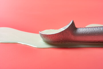 side view spoon with melted hami melon flavor ice cream on a pink background