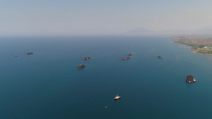Fototapeta na wymiar aerial view barges full coal anchored at sea near coal fired power station waiting be transported. coal barges and tugboats java, paiton indonesia