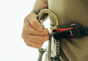Male climber holds a carabiner in his hand. Close-up on a white background.