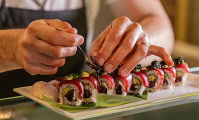 Chef’s hands decorating traditional japanese sushi