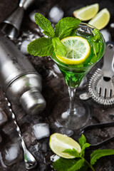 Glass with liquor or cocktail and bar accessories on dark background