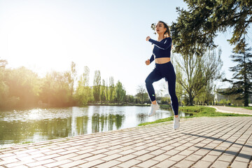 Athletic fit young woman jogging early in the morning in park