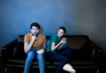 Obraz premium Young family sitting on the couch watching movies popcorn