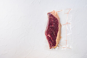 Raw picanha steak vacuum packed  organic beef meat   on white concrete  textured background, top view space for text.