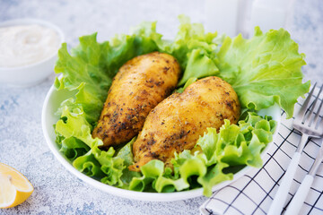 Chicken breasts baked in spices and oil with fresh herbs for dinner, healthy food on a light background