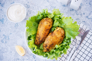 Chicken breasts baked in spices and oil with fresh herbs for dinner, healthy food on a light background, selective focus