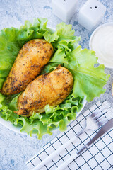 Chicken breasts baked in spices and oil with fresh herbs for dinner, healthy food on a light background, selective focus