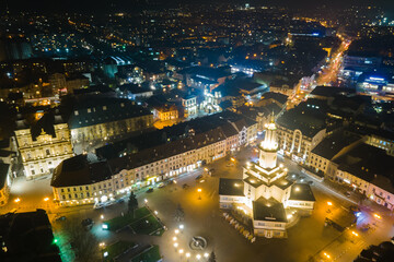 Aerial view of bright illuminated streets and buildings in Ukrainian Ivano-Frankivsk city center at night.