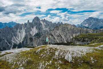 Aerial view of a woman hiker in green jacket against Cadini di Misurina mountain peaks in...