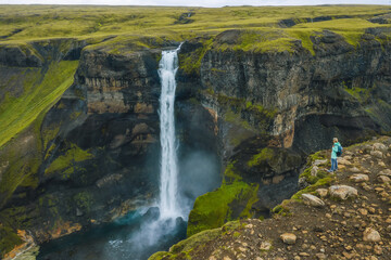 Aerial view of woman with backpack enjoying Haifoss waterfall of Iceland Highlands