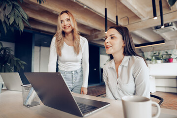 Obraz premium Two young female colleagues discussing business project together in office