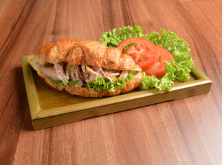 fried chicken or tuna fish with sesame sauce in baked crispy croissant bread and vegetables salad on wood table fresh halal pastry sandwich menu