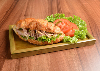 fried chicken or tuna fish with sesame sauce in baked crispy croissant bread and vegetables salad on wood table fresh halal pastry sandwich menu