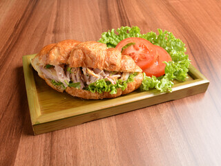 fried chicken or tuna fish with sesame sauce in baked crispy croissant bread and vegetables salad on wood table fresh halal pastry sandwich menu