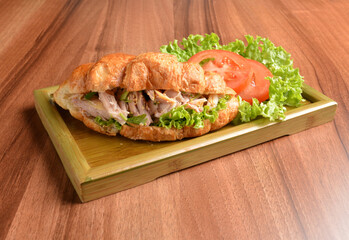 fried chicken or tuna fish with sesame sauce in baked crispy croissant bread and vegetables salad on wood table fresh halal pastry sandwich menu