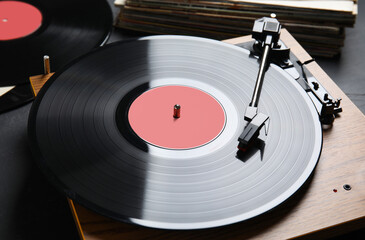 Modern vinyl record player with disc on black background, closeup