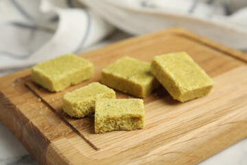 Many bouillon cubes on wooden board, closeup