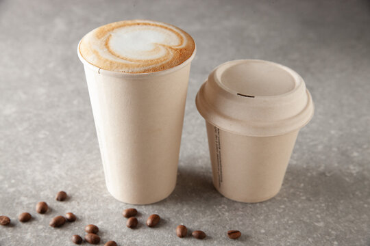Two paper coffee cup sizes on table full of warm beverage