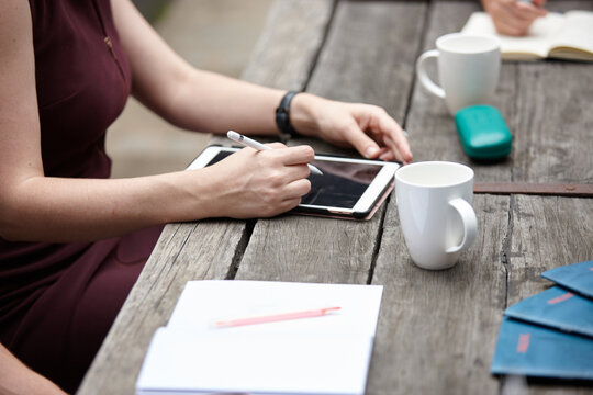 Woman working on touchpad outdoors with colleagues