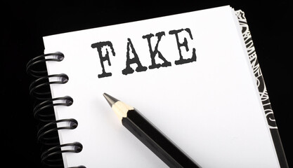 FAKE written text in small notebook on a black background