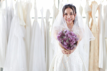 Close up face of Smiling The bride in a white lace dress hand holding a bouquet of purple flowers forward. Concept happy lovely love marry best day.