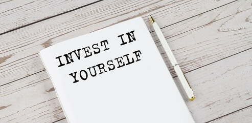 Notepad with text INVEST IN YOURSELF . White background. Business concept