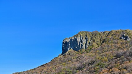 Fototapeta na wymiar 青空バックに見た紅葉に囲まれた断崖絶壁の情景＠積丹、北海道