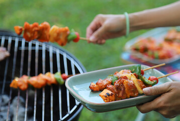 Closeup of  chicken barbecue on ceramic tray  with woman's hands.