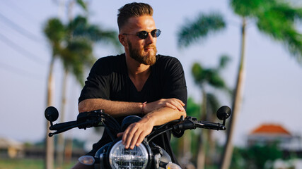 Young guy in dark clothes on a motorcycle wearing glasses