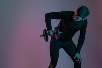 Muscular guy pumping up shoulder muscles with dumbbell