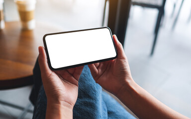 Mockup image of a woman holding mobile phone with blank white desktop screen