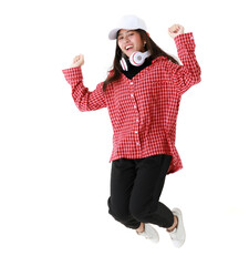 Delighted ethnic female in cool outfit and with headphones on neck in moment of jumping on white background in studio