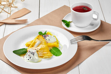 Crepes with sour cream, powdered sugar and fruit tea