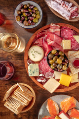 Italian antipasti or Spanish tapas with wine. Gourmet charcuterie and cheese board, shot from above on a rustic background. Salmon sandwiches, salami, Parma ham, blue cheese. Mediterranean buffet