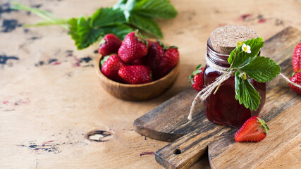 Strawberry jam in a jar on a wooden board. Fermented berries. Copy space.