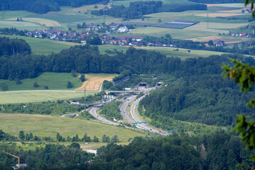 Rural landscape seen from local mountain Uetliberg on a summer day with highway and portal to Uetliberg tunnel. Photo taken June 29th, 2021, Zurich, Switzerland.